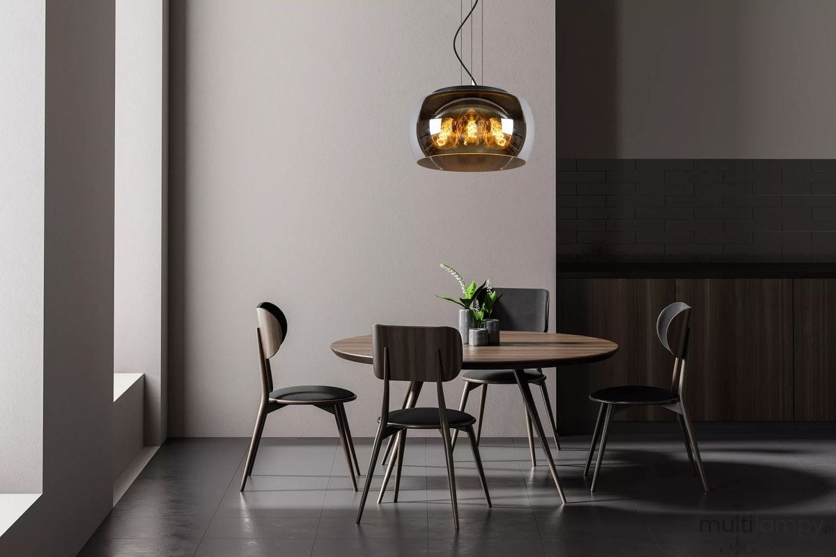 Lampa wisząca Olivia D40 w kolorze czarnym, 3-punktowa, z przezroczystym kloszem, zawieszona nad okrągłym drewnianym stołem w nowoczesnej aranżacji. W tle widoczne cztery krzesła oraz roślina w doniczce. Oświetlenie w stylu industrialnym.