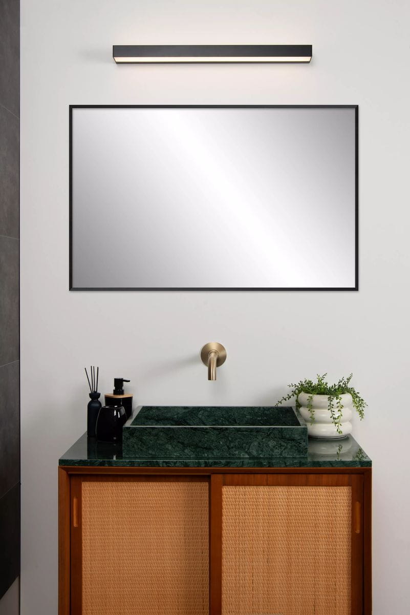 Kinkiet Alexa LED IP44 w kolorze czarnym, umieszczony nad lustrem. Prosty, prostokątny kształt z delikatnym, rozproszonym światłem. W tle widoczna umywalka z zielonym blatem i drewnianą szafką, tworząca nowoczesną aranżację łazienki.