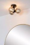 Czarna lampa sufitowa Trudy 3-punktowa, z trzema okrągłymi kloszami w kolorze złotym, zamontowana na suficie. Widok z dołu, lampa o nowoczesnym designie, w tle okrągłe lustro z złotą ramą.