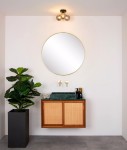 Lampa sufitowa Trudy 3-punktowa w kolorze czarnym, umieszczona w górnej części zdjęcia. Posiada trzy szklane klosze, które emitują światło, nad nowoczesną umywalką z marmurowym blatem i okrągłym lustrem w złotej ramie.