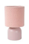 Różowa lampa stołowa Woolly z miękkim, teksturowanym abażurem i okrągłą podstawą. Abażur ma kształt cylindryczny, a podstawa jest gładka, w jasnym odcieniu różu. Produkt widoczny z boku, stojący na płaskiej powierzchni.
