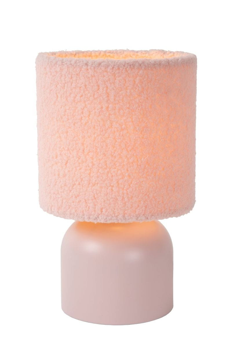Różowa lampa stołowa Woolly z okrągłą podstawą i kloszem o fakturze przypominającej wełnę. Klosz ma delikatny kształt cylindryczny, emitując ciepłe światło. Ujęcie frontalne, lampa stoi na gładkiej powierzchni.