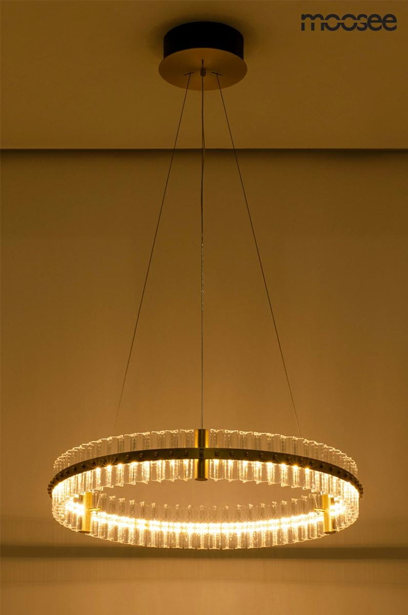 Lampa wisząca Saturnus LED 70 w kolorze złotym, okrągła, z przezroczystymi elementami, zawieszona na cienkich linkach. Widoczny elegancki pierścień z diodami LED, umieszczony pod sufitem na ciemnym tle.