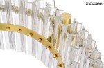 Lampa wisząca Saturnus Due LED 47, 1-punktowa, z okrągłą, złotą oprawą oraz przezroczystymi, teksturowanymi kloszami w kształcie prostokątów. Widoczna metalowa konstrukcja z dekoracyjnymi kulkami. Kąt ujęcia zbliżenie na detal lampy.