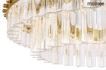 Lampa wisząca Saturnus Due LED 47 w kolorze złotym, z przezroczystymi, cylindrycznymi elementami szklanymi. Produkt ma jeden punkt świetlny, dekoracyjne złote detale i jest zawieszony na metalowej podstawie, widoczny z boku.