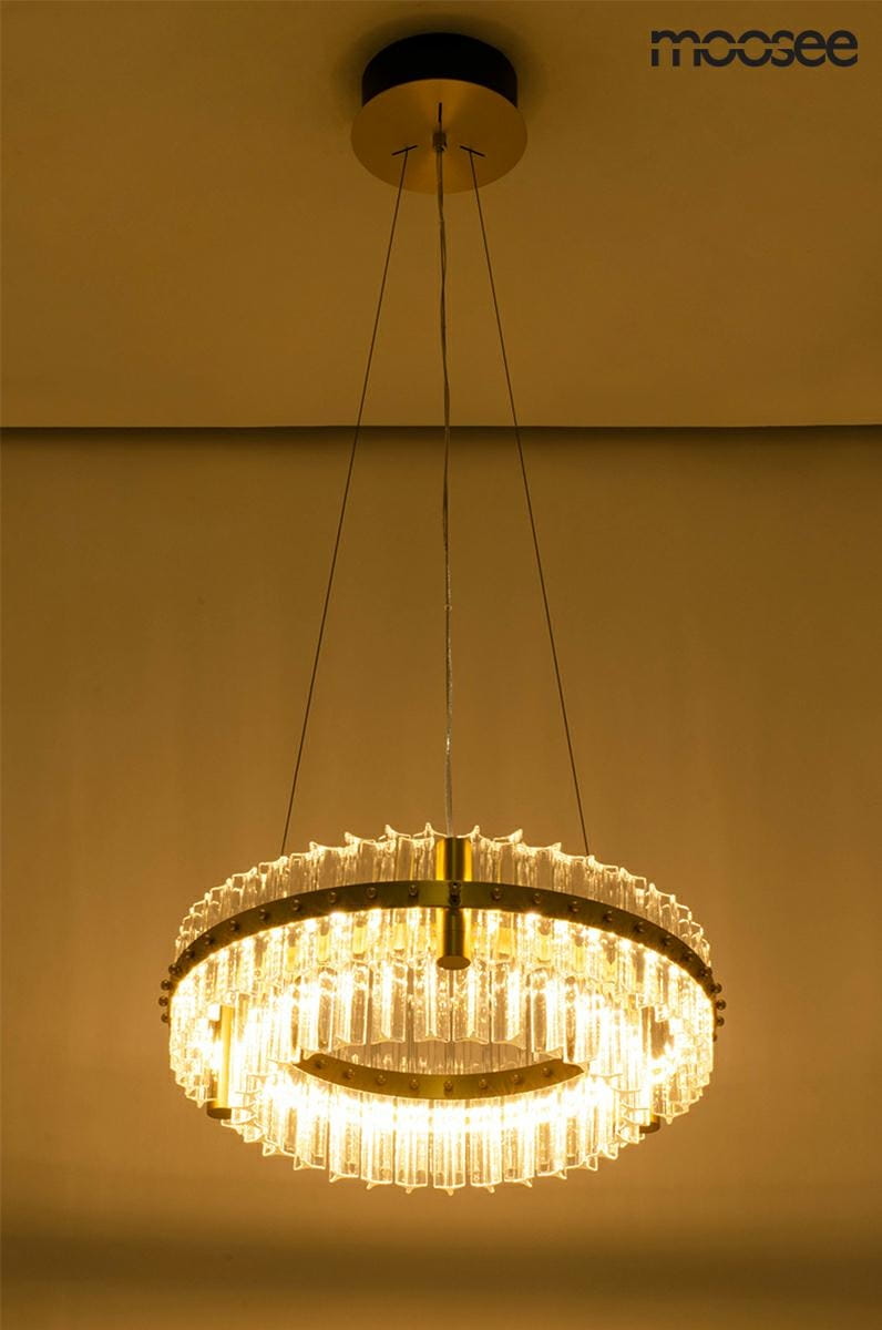 Lampa wisząca Saturnus Due LED o średnicy 47 cm, w złotym kolorze, z transparentnymi elementami szklanymi. Posiada okrągły kształt, zawieszona na cienkich kablach, emitująca ciepłe światło. Montaż sufitowy, idealna do nowoczesnych wnętrz.