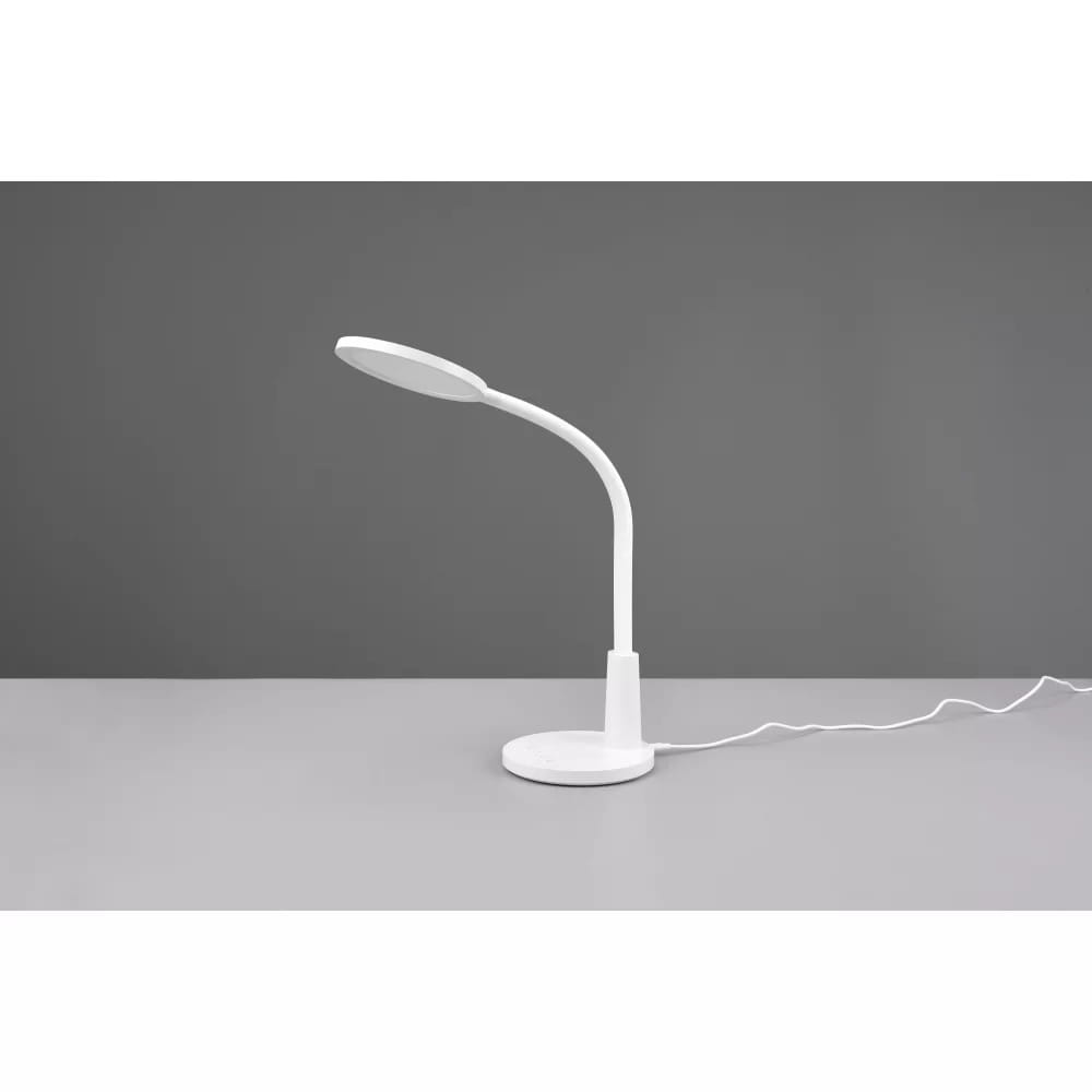 Biała lampa biurkowa LED Sally, 1-punktowa, z elastycznym ramieniem. Ujęcie z boku, na jasnym blacie, z okrągłą podstawą i przewodem zasilającym. Prosty, nowoczesny design, idealna do biura lub nauki.