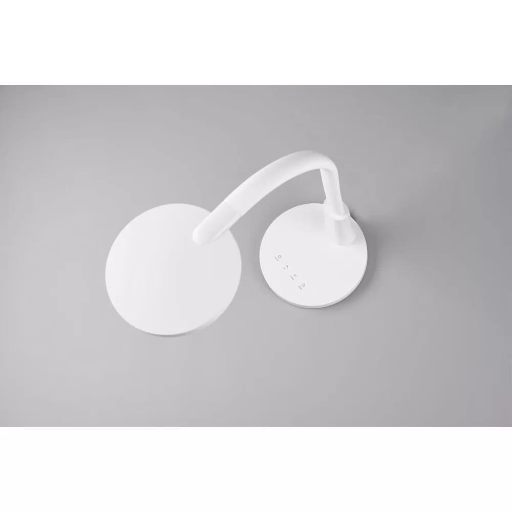 Biała lampa biurkowa LED Sally z elastyczną, zakrzywioną nogą i okrągłą podstawą. Widoczne przyciski sterujące na podstawie. Ujęcie z góry, na jednolitym szarym tle.