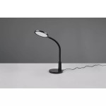 Czarna lampa biurkowa LED Sally z jednym punktem świetlnym, z elastycznym ramieniem i okrągłą podstawą. Ujęcie z boku na stole, z widocznym kablem zasilającym. Tło w odcieniu szarości.
