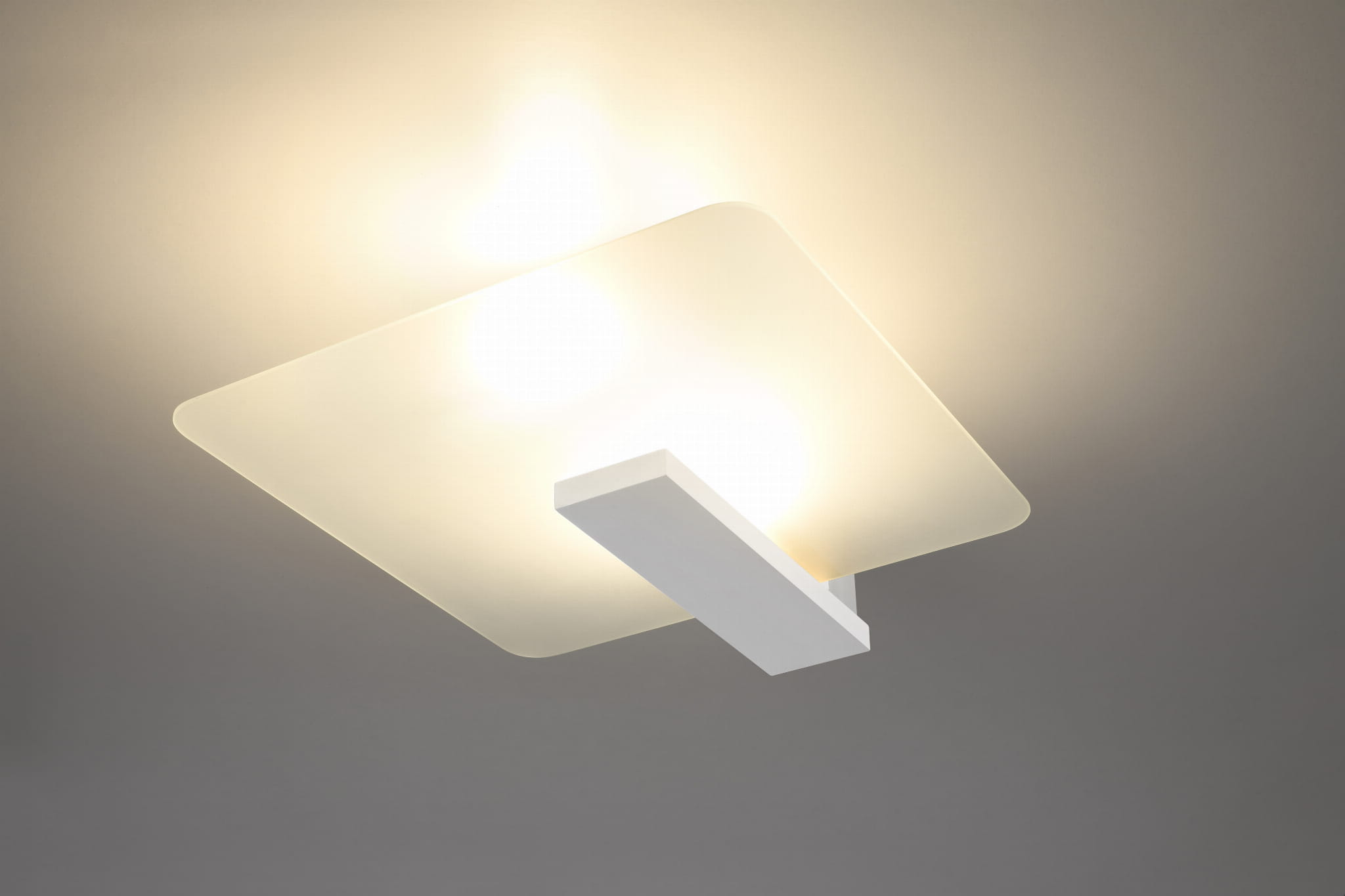 Lappo lampa sufitowa 2-punktowa w białym kolorze, z matowym kloszem w kształcie kwadratu i prostokątnym uchwytem. Ujęcie z dołu, ukazujące dwa źródła światła. Tło w odcieniu szarym, minimalistyczne, podkreślające nowoczesny design lampy.