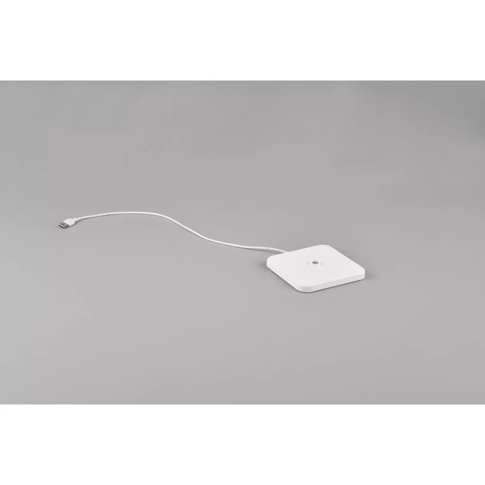 Biała lampa stołowa zewnętrzna Fernandez LED, o kwadratowej podstawie z gładką powierzchnią. Widoczny przewód USB. Lampa leży na szarym tle, ukazana z boku, co podkreśla jej minimalistyczny design.