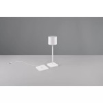 Biała lampa stołowa zewnętrzna Fernandez LED z cylindrycznym kloszem, umieszczona na prostokątnej podstawie. Widoczny kabel zasilający. Produkt ustawiony na szarym tle, w frontalnej perspektywie.