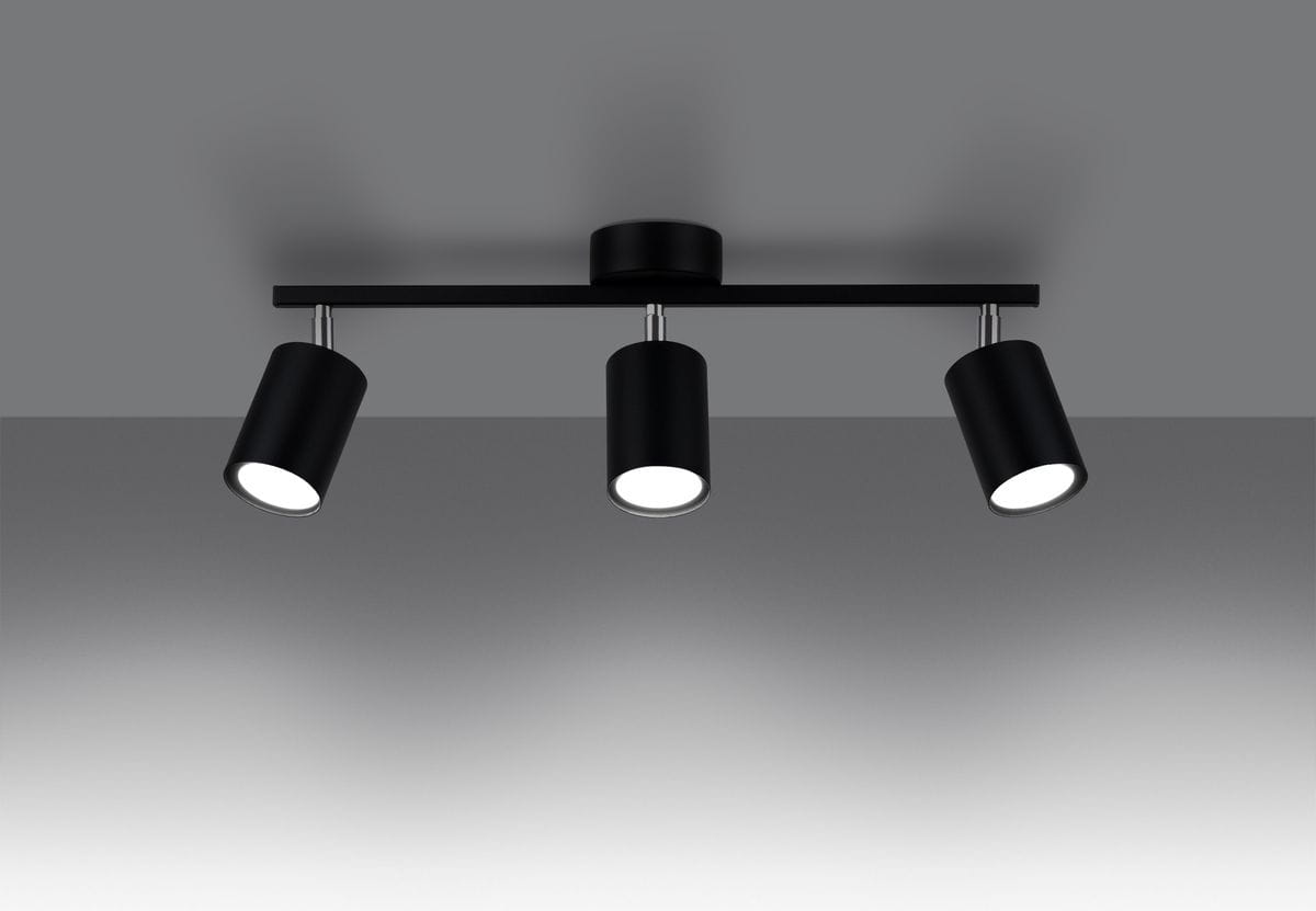 Czarna lampa sufitowa (spot) Lemmi, 3-punktowa, z cylindrycznymi kloszami, umieszczona na metalowej listwie. Klosze są skierowane w dół, co umożliwia kierunkowe oświetlenie. Tło w odcieniu szarości.