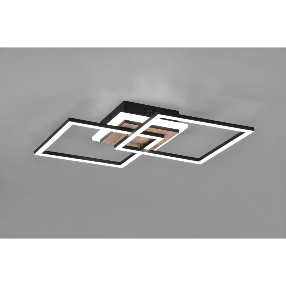 Czarna lampa sufitowa LED 3-punktowa z pilotem, składająca się z trzech geometrycznych ram w białej oprawie. Widoczna drewniana część centralna. Produkt zamontowany pod sufitem, na jednolitym tle.