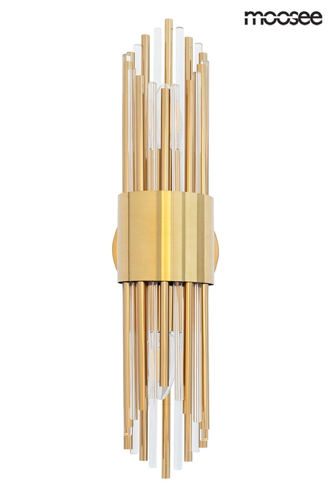 Kinkiet Amadeo 2-punktowy w złotym kolorze, z metalową podstawą i długimi, przezroczystymi oraz złotymi elementami. Ułożony pionowo, z widocznymi żarówkami w centralnej części. Tło białe, co podkreśla elegancki design lampy.