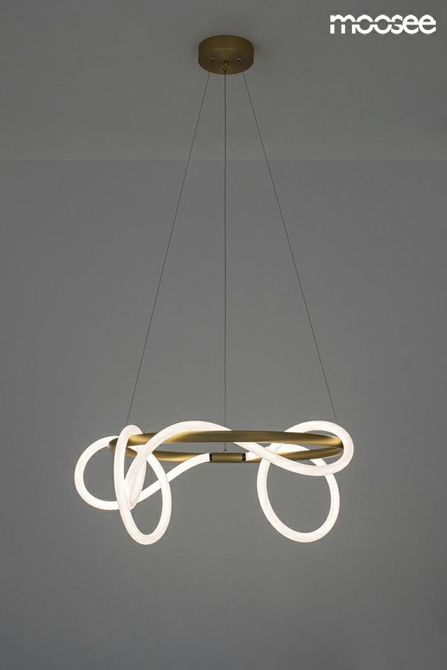 Lampa wisząca Serpiente 1-punktowa w kolorze złotym z elementami LED, o organicznych kształtach i białych, podświetlanych akcentach. Zamontowana na cienkich linkach, zawieszona pod sufitem na jednolitym, szarym tle.