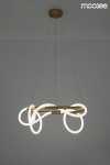 Lampa wisząca Serpiente 1-punktowa w kolorze złotym z elementami LED, o organicznych kształtach i białych, podświetlanych akcentach. Zamontowana na cienkich linkach, zawieszona pod sufitem na jednolitym, szarym tle.