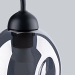 Czarny kinkiet Fillan z dymionym kloszem, z widocznym mocowaniem i kablem, w zbliżeniu na górną część lampy. Klosz o okrągłym kształcie, połyskujący, z czarnym elementem montażowym. Tło szare, neutralne.