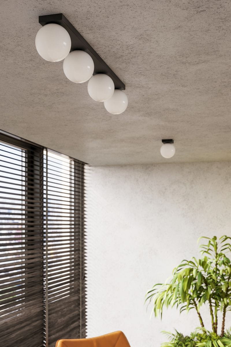 Czarna lampa sufitowa Yoli SL.1154 z czterema okrągłymi kloszami w kolorze białym. Ujęcie z dołu, zamontowana na suficie w nowoczesnym wnętrzu. Widoczne okno z roletami oraz roślina w tle, co nadaje kontekst aranżacji.
