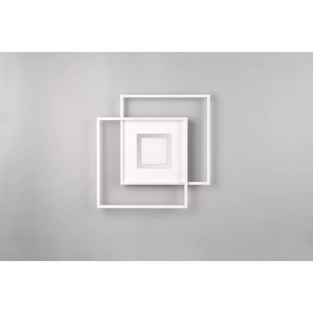 Biała lampa sufitowa Via LED 3-punktowa z pilotem, składająca się z dwóch kwadratowych ram, z centralnym panelem LED w środku. Produkt zamontowany na szarym tle, ukazujący nowoczesny design i minimalistyczny styl.