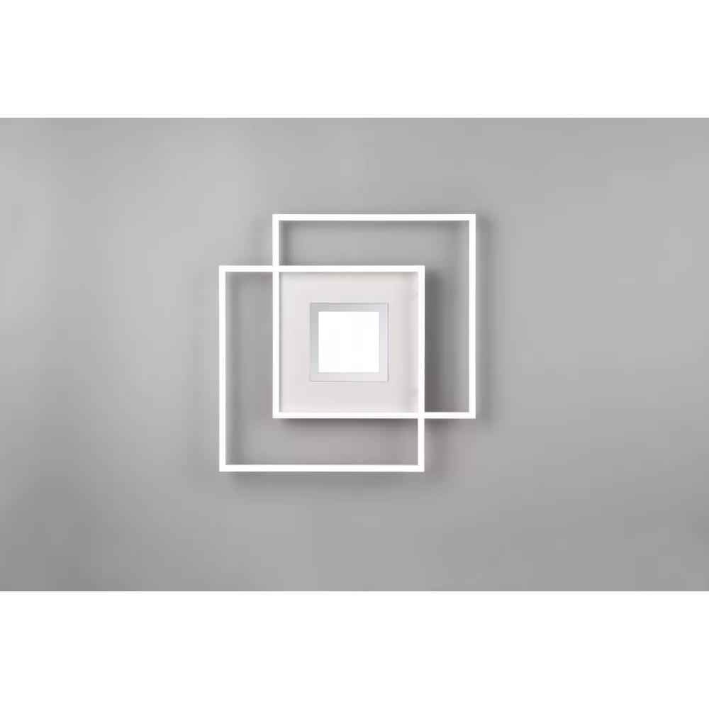 Biała lampa sufitowa Via LED 3-punktowa z pilotem, składająca się z trzech nachodzących na siebie prostokątów. Ujęcie frontalne, produkt zamontowany na szarym tle. Centralny kwadratowy panel LED w jasnej oprawie.