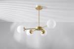 Lampa sufitowa 4-punktowa w kolorze mosiądzu z białymi, okrągłymi kloszami. Produkt zamontowany na suficie, z czterema ramionami rozciągającymi się w różnych kierunkach. Proste, nowoczesne wzornictwo, idealne do wnętrz.