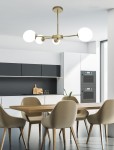 Lampa sufitowa 4-punktowa w kolorze mosiądzu z trzema okrągłymi, białymi kloszami. Zawieszona w nowoczesnej kuchni, nad drewnianym stołem, z jasnym tłem i szafkami w odcieniach bieli i czerni.