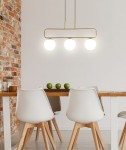Lampa wisząca Jove 3-punktowa w kolorze mosiądzu z trzema okrągłymi kloszami. Zawieszona poziomo nad stołem, w nowoczesnej aranżacji z białymi krzesłami i drewnianym blatem. Tło z cegły podkreśla jej elegancki design.