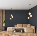 Duo lampa wisząca 3-punktowa w kolorze czarnym i złotym, z trzema okrągłymi, białymi kloszami, zawieszona na cienkich linkach. Lampa znajduje się w nowoczesnym wnętrzu z szarymi ścianami i drewnianą podłogą, obok kanapy i stolika kawowego.