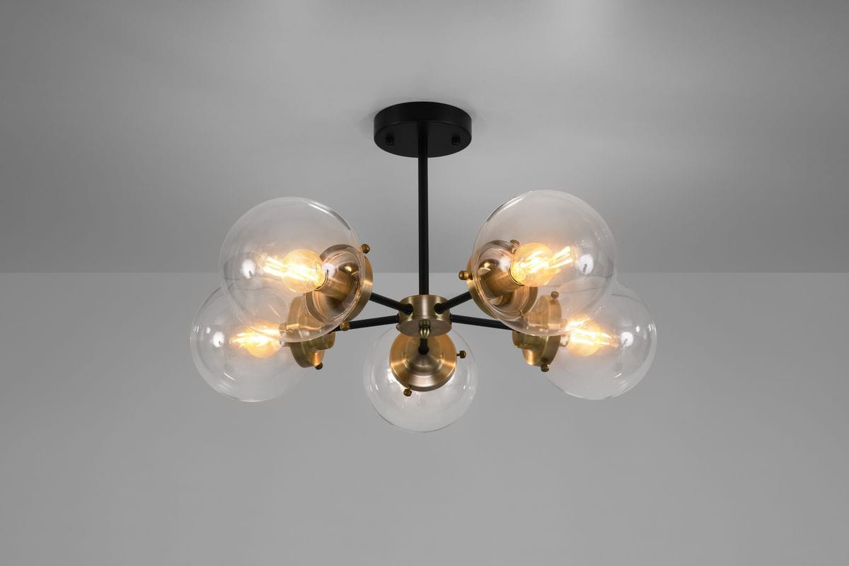 Lampa sufitowa Lens w kolorze czarnym i patynowym, 5-punktowa. Szklane klosze w kształcie kul, z widocznymi żarówkami, zamontowana na czarnym stelażu. Ujęcie z dołu, eksponujące detale konstrukcji.