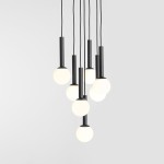 Lampa wisząca Riu 7-punktowa w kolorze czarnym, z siedmioma okrągłymi, białymi kloszami. Ujęcie z góry, pokazujące różne długości zwisających przewodów. Prosty, nowoczesny design, idealna do wnętrz. Tło jasnoszare.