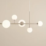 Lampa wisząca Dione 6-punktowa w beżowym kolorze, z sześcioma okrągłymi kloszami w białym szkłach, zamontowana na metalowej, poziomej ramie. Widok z góry, na jednolitym tle.