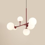 Lampa wisząca Dione w kolorze czerwonym z sześcioma białymi, okrągłymi kloszami. Produkt zawieszony na cienkim, czarnym przewodzie, z symetrycznym układem ramion, położony w centralnej części zdjęcia na beżowym tle.