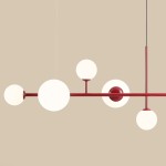Lampa wisząca Dione 6-punktowa w kolorze czerwonym, z pięcioma okrągłymi kloszami w białym kolorze, umieszczonymi na poziomej rurze. Klosze różnej wielkości, z centralną kulistą podstawą. Produkt zawieszony na cienkim przewodzie na tle jasnobeżowym.