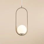 Lampa wisząca Riva 1-punktowa w kolorze beżowym z okrągłą, białą kulą. Konstrukcja o minimalistycznym kształcie, zawieszona na cienkim przewodzie, umieszczona na jednolitym tle. Idealna do nowoczesnych wnętrz.