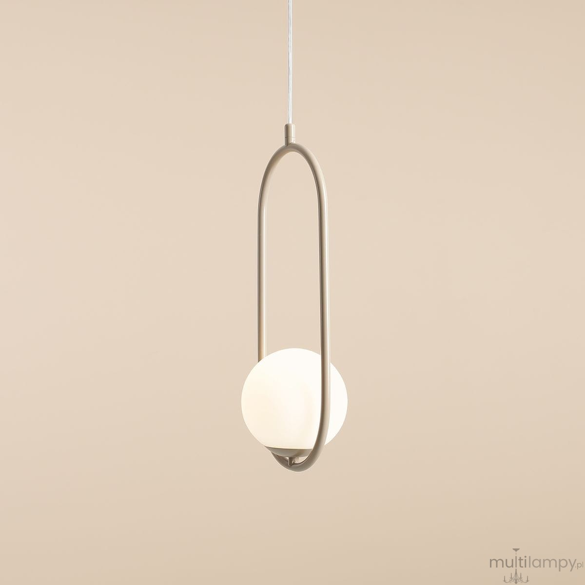 Lampa wisząca Riva 1-punktowa w kolorze beżowym, z okrągłym kloszem w białym kolorze, zawieszona na cienkim, białym przewodzie. Produkt ma minimalistyczny kształt z eliptycznym ramieniem, umieszczonym w centralnej części. Tło w odcieniu beżowym.