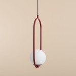 Czerwona lampa wisząca Riva 1-punktowa z okrągłym, białym kloszem, zawieszona na cienkim kablu. Kształt lampy podkreśla minimalistyczny design z owalnym metalowym ramieniem. Tło w jasnym odcieniu.
