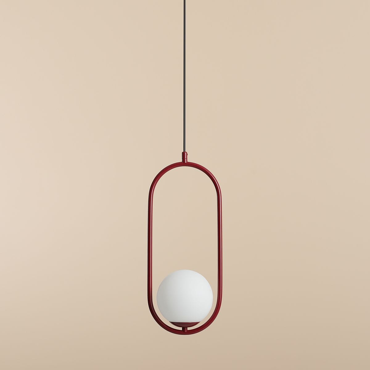 Riva lampa wisząca 1-punktowa w kolorze czerwonym z białym okrągłym kloszem. Produkt zawieszony na cienkim czarnym przewodzie, posiada nowoczesny, minimalistyczny design. Tło w kolorze jasnego beżu.
