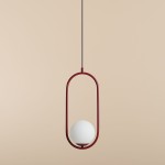 Riva lampa wisząca 1-punktowa w kolorze czerwonym z białym okrągłym kloszem. Produkt zawieszony na cienkim czarnym przewodzie, posiada nowoczesny, minimalistyczny design. Tło w kolorze jasnego beżu.