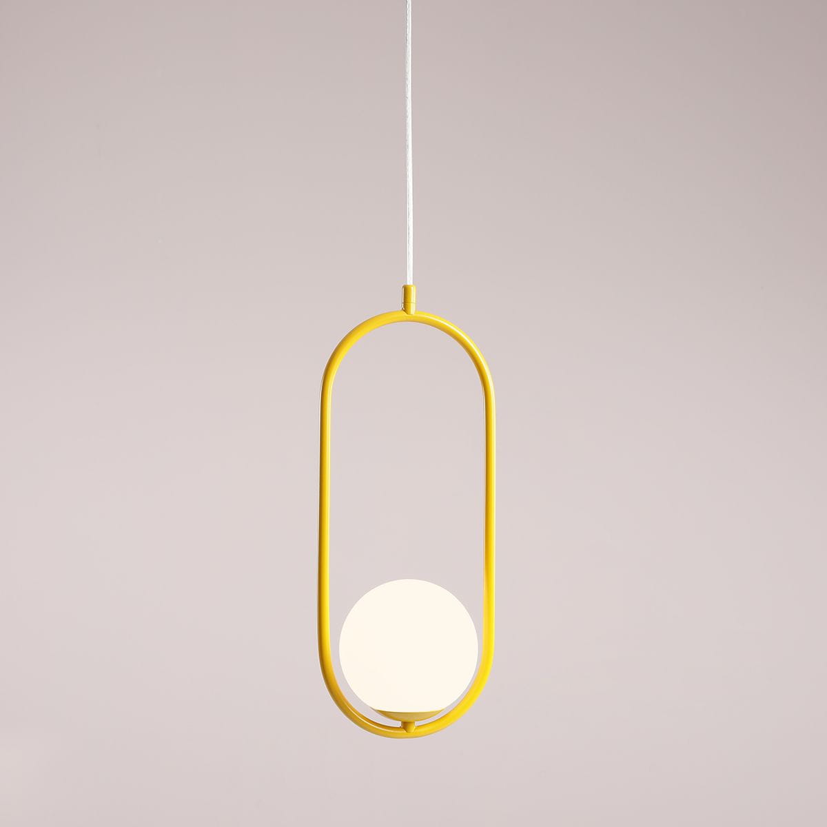 Żółta lampa wisząca Riva 1-punktowa z okrągłym, białym kloszem, zawieszona na białym przewodzie. Okrągła forma klosza osadzona w stylowej, metalowej ramie. Tło w jednolitym, jasnym kolorze.