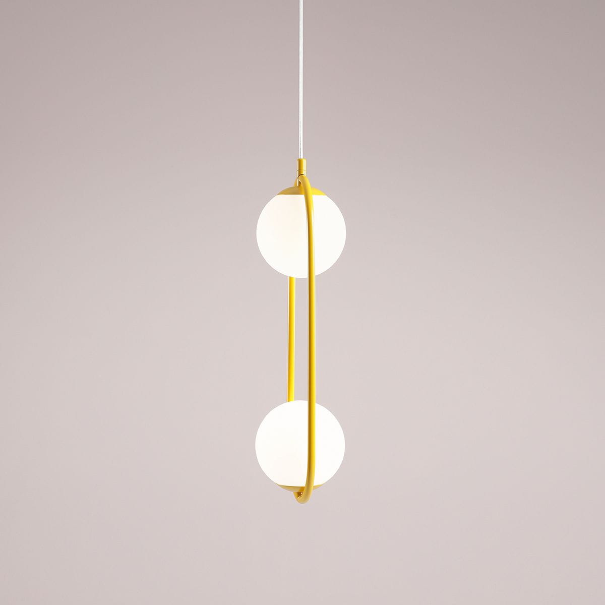 Lampa wisząca Riva 2-punktowa w kolorze żółtym, z dwoma okrągłymi, białymi kloszami, zawieszona na cienkim białym przewodzie. Klosze umieszczone są na żółtej, elastycznej ramie, tworząc nowoczesny, minimalistyczny wygląd.