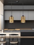 Cox lampa wisząca 2-punktowa w kolorze czarnym i złotym. Lampa zawieszona na czarnym stelażu, z dwoma cylindrycznymi kloszami w złotym, teksturowanym wykończeniu. Ujęcie z przodu, w nowoczesnej kuchni z drewnianym blatem i czarnymi krzesłami.