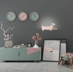 Różowy kinkiet LED w kształcie psa, zamontowany na szarej ścianie. Produkt ma minimalistyczny design, z widoczną drewnianą półką. W otoczeniu dekoracyjna doniczka, zegary w pastelowych kolorach oraz stylowe meble.