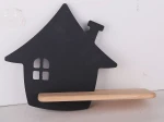 Czarny kinkiet LED w kształcie domu, z wyciętymi oknami. Posiada drewniany półkę pod lampą. Produkt zawieszony na jasnym tle, widoczny z przodu. Idealny do nowoczesnych wnętrz.