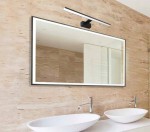 Besta kinkiet łazienkowy LED IP44 w kolorze czarnym, zamontowany nad prostokątnym lustrem. Oświetlenie w minimalistycznym stylu, skierowane w dół, na tle jasnej ściany marmurowej. Wysokość 60 cm, moc 15W.