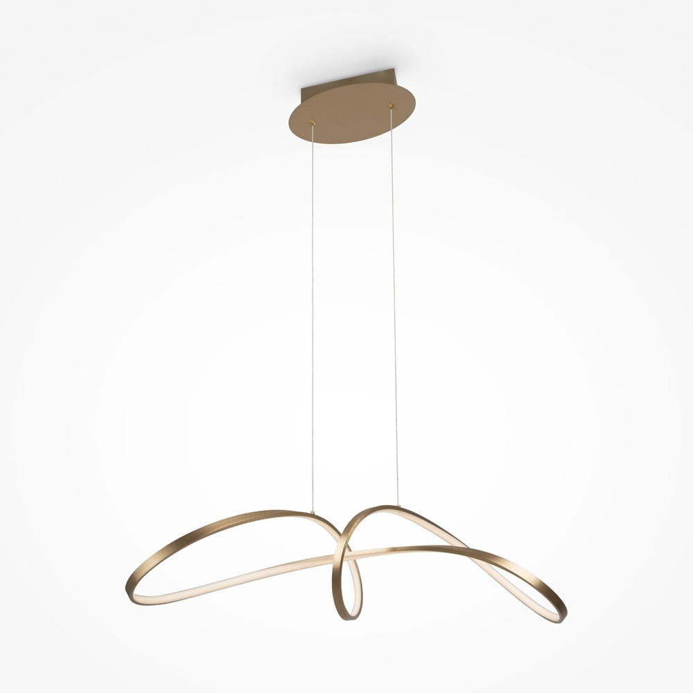 Złota lampa wisząca Curve LED z unikalną, falistą formą. Posiada dwa smukłe, okrągłe elementy z podświetleniem LED, zawieszona na cienkich linkach. Montaż sufitowy na okrągłej podstawie. Proste, jasne tło podkreśla elegancki design.