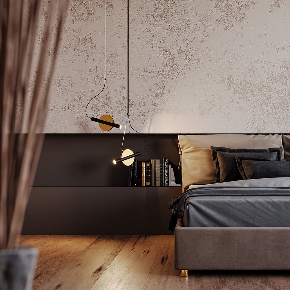 Enigma LED lampa wisząca 1-punktowa w kolorze mosiądzu, zawieszona nad łóżkiem w sypialni. Lampa ma minimalistyczny design z okrągłym elementem i źródłem światła, umieszczona w nowoczesnym wnętrzu z książkami na półce.