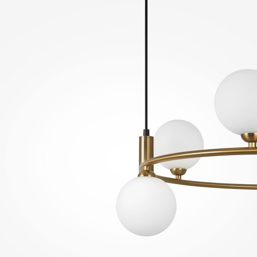 Lampa wisząca Ring 6-punktowa w kolorze mosiądzu, z trzema białymi, okrągłymi kloszami. Produkt zawieszony na czarnym przewodzie, z widoczną metalową konstrukcją w kształcie okręgu. Zbliżenie na detale.