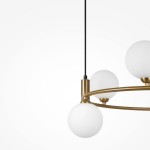 Lampa wisząca Ring 6-punktowa w kolorze mosiądzu, z trzema białymi, okrągłymi kloszami. Produkt zawieszony na czarnym przewodzie, z widoczną metalową konstrukcją w kształcie okręgu. Zbliżenie na detale.