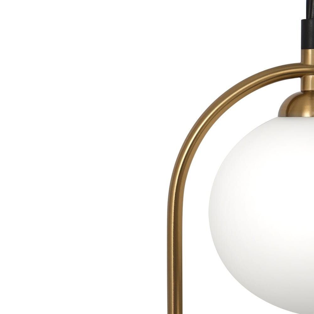 Lampa wisząca 2-punktowa w kolorze mosiądzu z białym szklanym kloszem. Ujęcie z boku, z widocznym okrągłym kloszem zawieszonym na cienkim, złotym ramieniu. Elegancki design, idealna do nowoczesnych wnętrz.